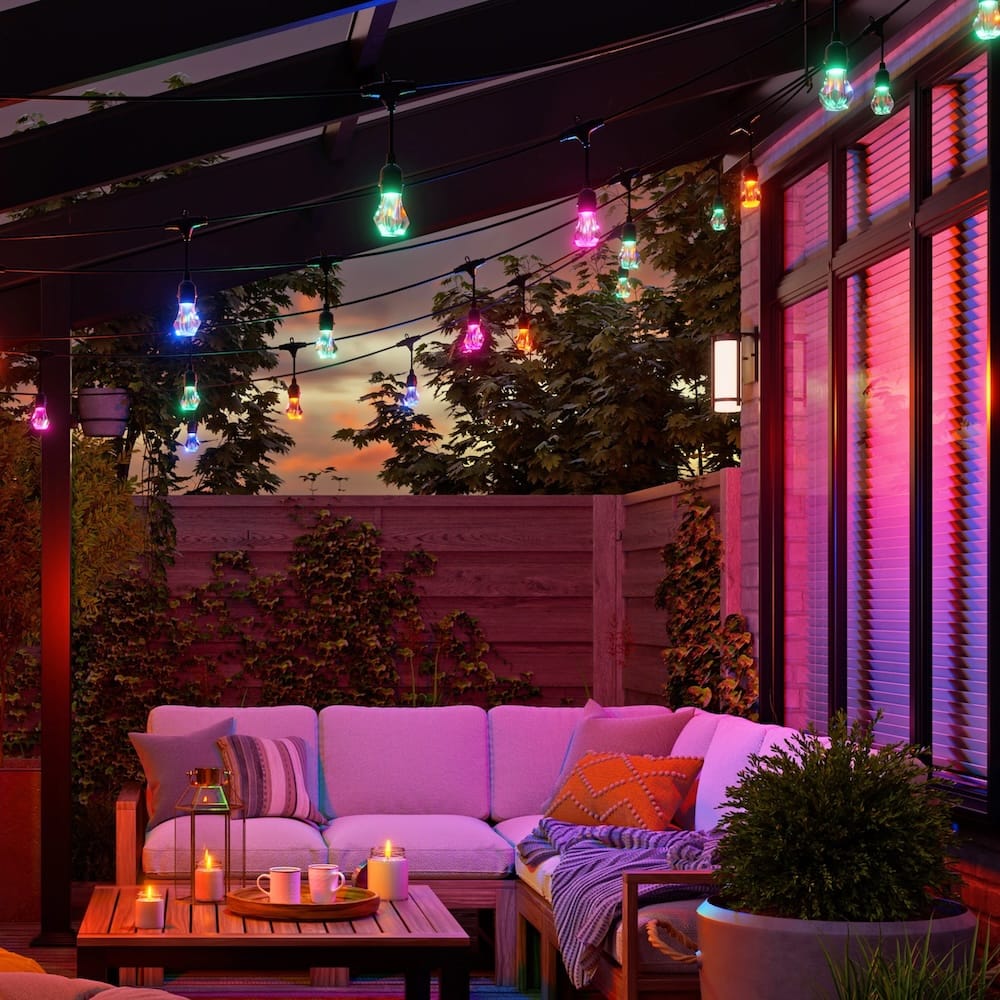 Outdoor seating area with multi coloured string lights hanging above.