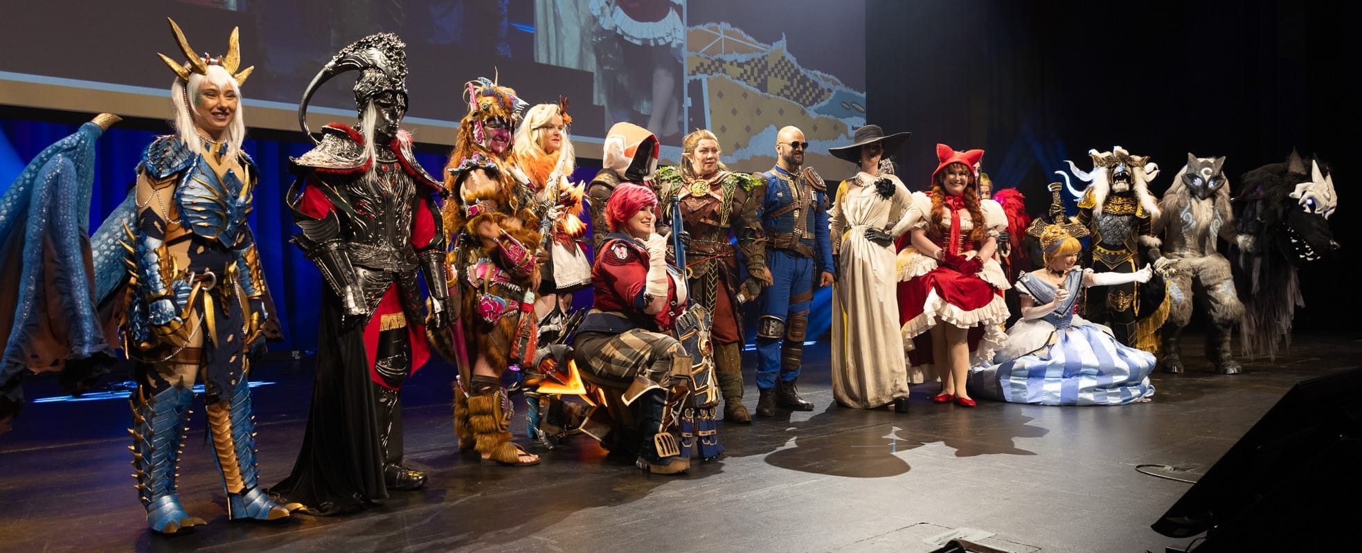 Many cosplayers (around 14) spread across a stage in a wide range of costumes. Cool poses galore.